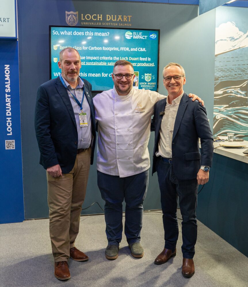 Three men stand together at a Seafood Expo event with Loch Duart branding